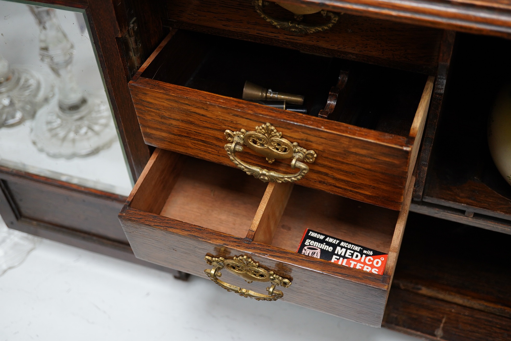 A carved oak smokers cabinet with Cartonware tobacco jar, cigar pricker and amber mouthpiece, 42cm wide. Condition - fair to good